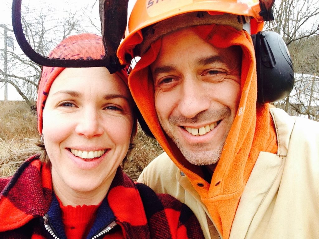 Autumn Stoscheck and Ezra Sherman of Eve's Cidery smiling outdoors in orchard work clothing.