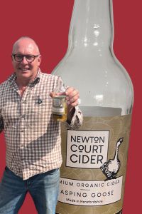 Cider Chat episode 471 – Paul Stephens of Newton Court Cider holding a bottle of Gasping Goose cider at the cidery in Herefordshire, UK.