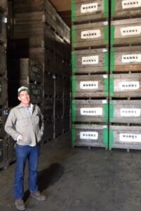 Jake Mann stands inside a cold storage facility beside towering stacks of apple bins at Five Mile Orchard in California's Pajaro Valley.