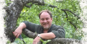 Ben Watson smiling while standing in an apple tree with pruning shears